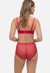 Conjunto de lencería rojo que incluye un sujetador de encaje transparente con tirantes ajustables y una braga de cintura alta con un patrón de lunares y acentos de encaje.