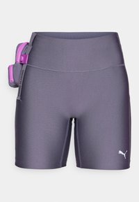 Lilla idrettsshorts med en jevn tekstur, med en sidelomme med en lys rosa glidelås og en hvit logo på det nedre beinet.