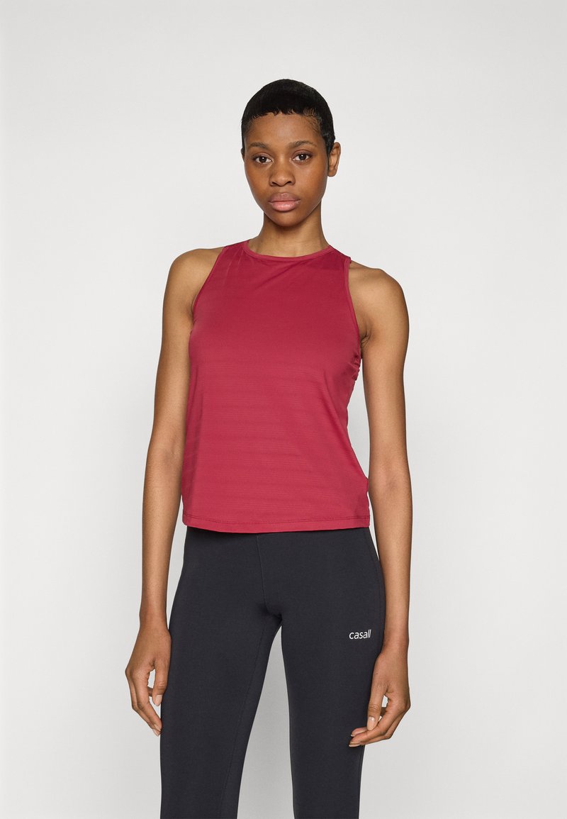 Burgundy ärmlös träningslinne i en smidig, stretchig tyg med rund halsringning, kombinerat med svarta tajta leggings med en logotyp.