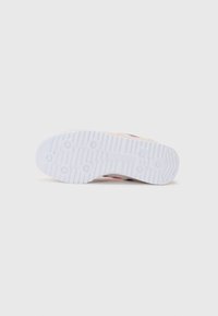 Semelle extérieure de chaussure de sport blanche avec des rainures texturées et des grips circulaires. Présente des accents rose pâle et un talon plat pour la stabilité.