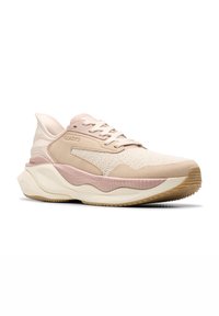 Zapato deportivo de color rosa claro y beige con una parte superior de tela texturizada, detalles lisos y una suela gruesa segmentada para amortiguación.