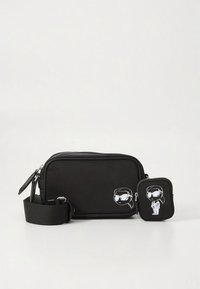 Zwarte nylon crossbodytas met een gladde textuur, voorzien van een ritssluiting en cartoonafbeeldingen aan de voorkant. Inclusief een kleinere bijpassende etui.