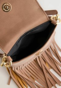 Beige faux suede táska arany硬件，nyitott tetejű，fekete belső，fringe díszítéssel. A belső rész nem tartalmaz további rekeszeket.