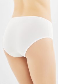Slip in cotone bianco con texture liscia e vita elastica. Design semplice, senza motivi o decorazioni, adatto per l'uso quotidiano.