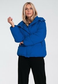 Niebieska kurtka puchowa z wyraźną konstrukcją, zapięciem na zatrzaski i wysokim kołnierzem. Wyposażona w ocieplenie, o gładkiej teksturze materiału.