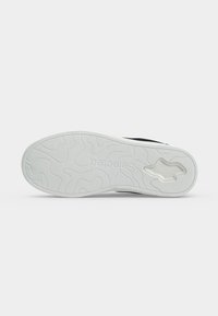 Semelle de chaussure blanche avec motif ondulé texturé, un logo en creux près du talon et le nom de la marque "Selected" embossé au centre.