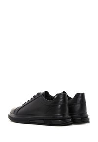Sneaker nere in pelle con finitura liscia, punta tonda e suola in gomma. Presentano una chiusura con lacci e un design minimalista.