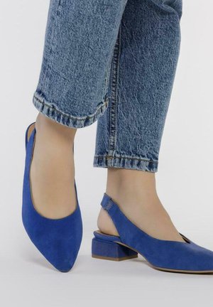 Zapatos slingback de ante azul con tacón bajo y punta afilada, combinados con jeans de mezclilla recortados y con dobladillo.