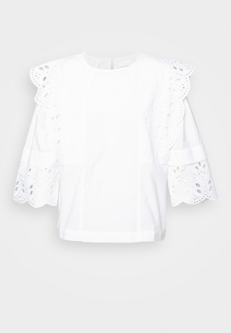 Chemisier blanc avec une finition en œillet texturé sur les manches et le col, comportant des manches courtes bouffantes et une coupe droite.