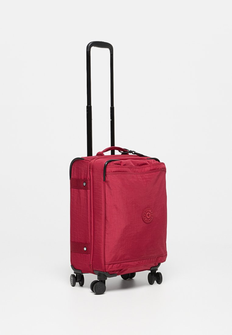 Roter Stoffkoffer mit strukturierter Oberfläche, ausziehbarem schwarzen Griff, vier Rädern und einem runden Logo an der Seite.