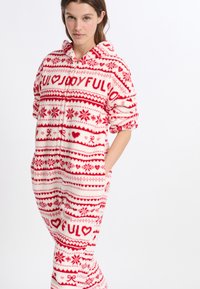 Rot-weißer Fleece-Overall mit Kapuze, verziert mit Herzen und Schneeflocken, zwei Seitentaschen und einer weichen, plüschigen Textur.