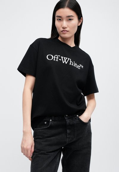 Czarna bawełniana koszulka z krótkim rękawem, z białym logo "Off-White". Okrągły dekolt, luźny krój, w połączeniu z czarnymi dżinsami.