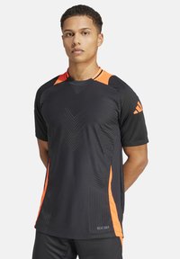 Zwart sportshirt met oranje accenten. Heeft een ronde hals, korte mouwen, gemêleerde patronen en een "HEAT.RDY" label aan de onderkant.