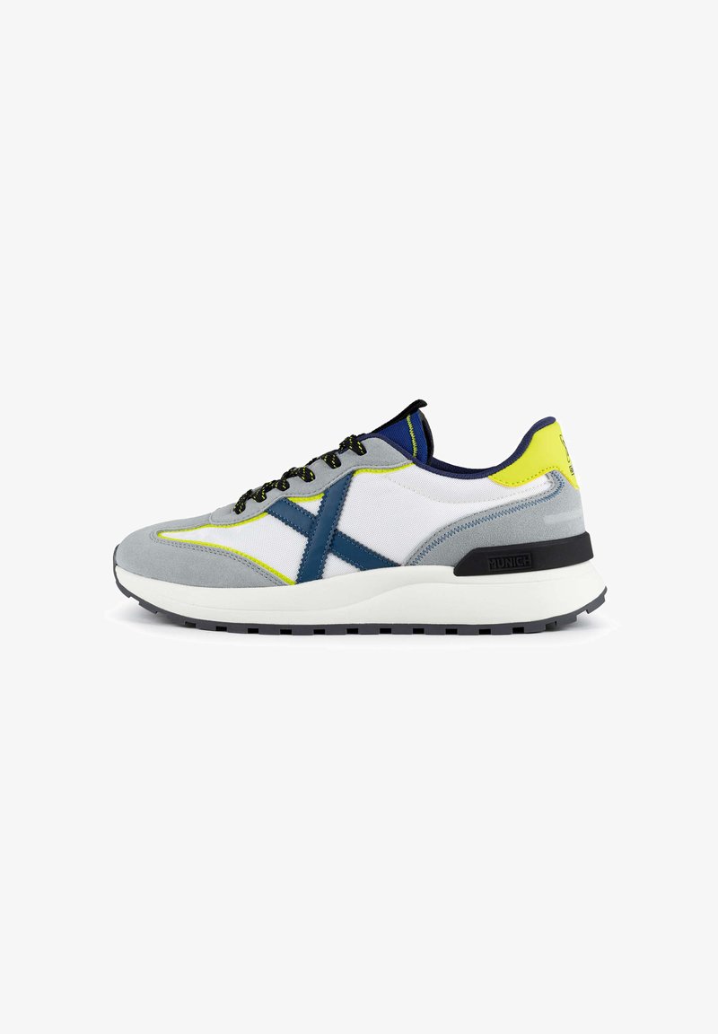 Baskets pour hommes, en daim gris et maille blanche, avec des accents bleus, des touches jaunes, des lacets noirs et une semelle en caoutchouc texturé.