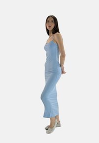 Robe maxi ajustée bleu clair avec de fines bretelles, texture côtelée et un éclat subtil. Assortie à des ballerines argentées et étincelantes.