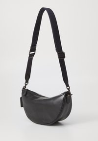 Borsa a spalla in pelle nera con una forma curva, caratterizzata da una tracolla in tessuto scuro removibile e una chiusura con zip. Texture liscia, design minimal.