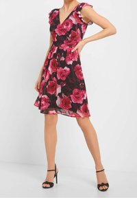 Sukienka w kwiaty z różowymi, czerwonymi i czarnymi różami. Posiada dekolt w kształcie litery V i falujące rękawy, wykonana z lekkiego materiału, do kolan.