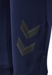 Marina atletiska leggings i strukturerad tyg, med en svart vågig chevrondesign på sidan och en sidoficka med dragkedja.