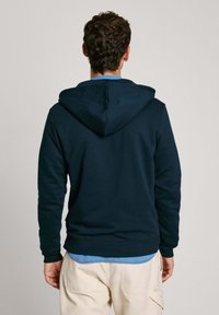 Sudadera con capucha en azul marino, hecha de una tela suave, que cuenta con un bolsillo tipo canguro, puños de canalé y una capucha ajustable con cordones.