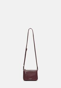 Bordowa skórzana torba na ramię z regulowanym paskiem, gładką teksturą i logo z przodu. Kompaktowy, prostokątny kształt.