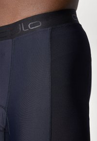 Shorts de sport noirs avec une taille élastique dotée d'un logo en relief, fabriqués dans un matériau lisse et respirant, avec une coupe ajustée.