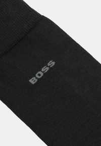 Calzini neri realizzati in tessuto lavorato a maglia liscio, con un logo "BOSS" grigio a contrasto vicino alla parte superiore.