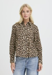 Cămașă cu imprimeu de leopard, în tonuri de bej și negru, cu guler, mâneci lungi și bordură dreaptă. Materialul are o textură netedă.