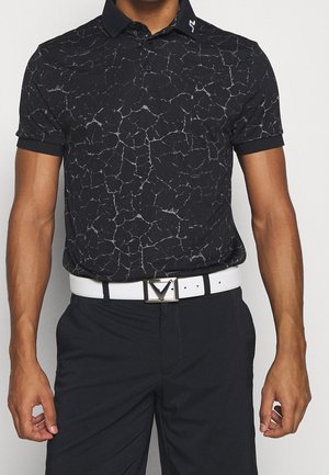 Uomo che indossa una polo nera con motivo screpolato, pantaloni neri e cintura bianca con fibbia rettangolare argento, mostrato dalle spalle ai fianchi.