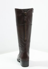 Botte montante en cuir marron avec une fermeture éclair latérale, surface légèrement texturée, talon carré et bout arrondi.