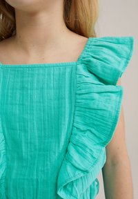 Tyrkysový top z látky s volánkovými krátkými rukávy, texturovaný povrch, čtvercový výstřih a nařasené detaily podél okrajů.
