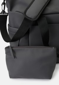 Mochila preta mate com um tecido durável, alça ajustável e uma bolsa com fecho éclair menor anexada à frente.