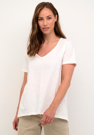 T-shirt blanc à manches courtes en V, fabriqué en tissu léger, avec une coupe décontractée et un ourlet qui tombe légèrement en dessous de la taille.