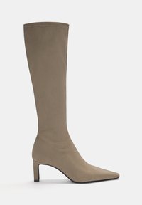 Botte mi-haute en daim taupe avec bout pointu et talon bloc de hauteur moyenne, présentée sur un fond uni clair.