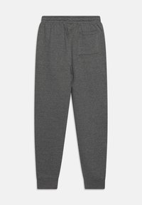 Pantalones de chándal grises hechos de tela suave, con cintura elástica, tobillos ajustados y un solo bolsillo trasero. Diseño simple y discreto.