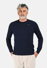 Maglione da uomo blu navy realizzato in tessuto morbido, con collo rotondo, polsini a costine e un piccolo logo sul petto.