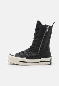 Høytopp svart lær sneakers med glidelås, rund tå, kontrasterende hvit såle og svarte snøringer, med teksturert design og logo.