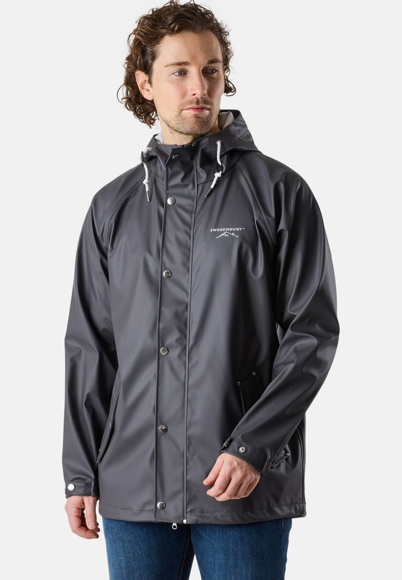 Veste étanche grise avec capuche, boutons-pression, cordons de serrage ajustables et deux poches latérales. Texture lisse avec un logo sur la poitrine.