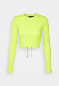 Top cropped a maniche lunghe in vivace tessuto a coste verde neon. Presenta un girocollo e due dettagli in catena argentata sul bordo.