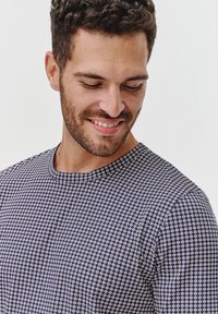 Granatowa koszulka z wzorem, okrągłym dekoltem, z siatkowym wzorem w kolorze kremowym i jasnobrązowym, wykonana z miękkiego, teksturowanego materiału.