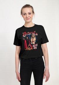 Svart bomull t-shirt med en grafisk tryck av "Dracula" med texten "BITE ME", som visar djärva färger och detaljerade illustrationer.