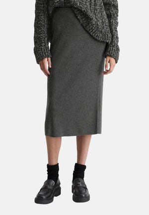 Grijze knielange rok van zachte gebreide stof, gecombineerd met een chunky gebreid sweater en zwarte platform loafers met dikke sokken.
