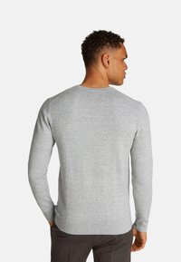 Suéter de punto gris con mangas largas, cuello y dobladillo acanalados, y tejido texturizado, visto desde la parte de atrás.