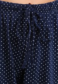 Navy blue spodnie w białe kropki wykonane z miękkiego materiału, z elastycznym paskiem w talii i detalem związu dla dostosowywanego dopasowania.