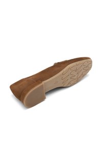 Scarpa piatta in suede marrone con punta quadrata e tacco basso a blocco. La suola presenta un motivo in gomma testurizzata per una migliore aderenza.