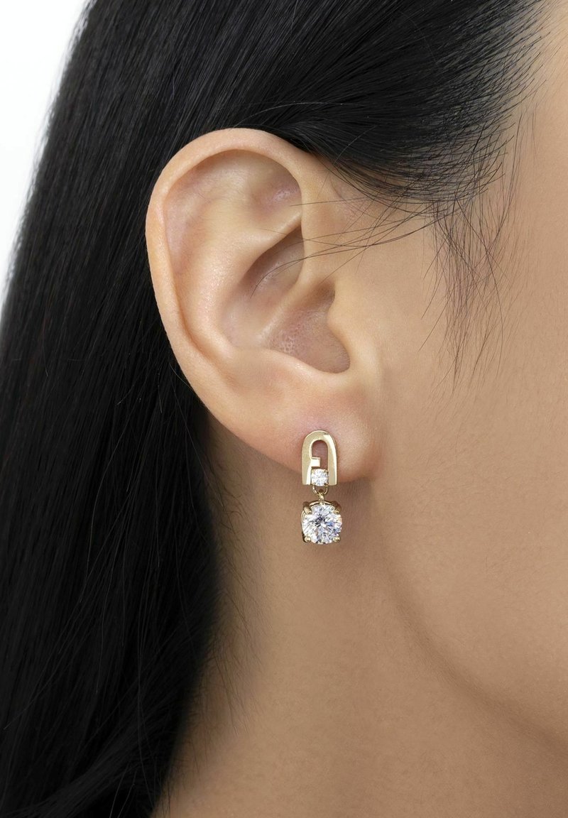 Boucles d'oreilles en or en forme de créoles, ornées d'un petit cristal rond et d'un plus grand cristal carré suspendu en dessous, le tout sur une oreille lisse.