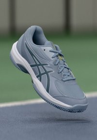 Lichtblauwe sportschoen met een gestructureerde bovenkant, voorzien van een grijze accentstripe en een contrasterende witte zool. Ontworpen voor prestatie en comfort.