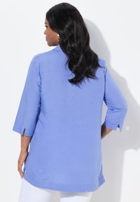 Tunic azzurro chiaro con maniche a tre quarti, fessure laterali e un taglio morbido. Tessuto liscio con un delicato motivo tessuto.