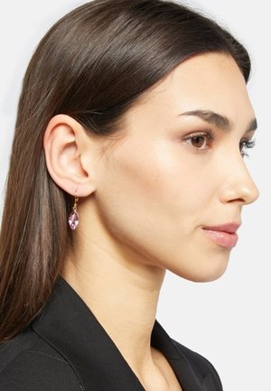 Boucles d'oreilles en améthyste présentant une forme marquise, du matériel doré et un lustre poli, portées sur l'oreille d'un mannequin sur un fond neutre.