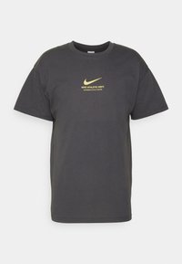 Šedé bavlněné tričko s krátkým rukávem, s zlatým logem Nike a textem "NIKE ATHLETIC DEPT. ENGINEERED FOR ALL ATHLETES."