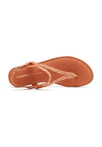 Sandalia de ante marrón con tiras trenzadas que presentan cuentas decorativas, suela plana y correa para el tobillo. Textura suave y diseño minimalista.